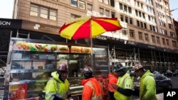 Construction workers buy food from a street cart in front of a building that has been chosen by Google as part of its expansion plans in New York, Dec. 17, 2018.