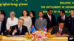 FILE - Australian Immigration Minister Scott Morrison, front left, signs a document together with Cambodian Interior Minister Sar Kheng, front right, during a ceremony for a controversial deal to resettle refugees in Phnom Penh, Cambodia, Sept. 26, 2014