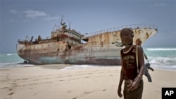 Masked Somali pirate Abdi Ali stands near a Taiwanese fishing vessel.