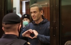 FILE - A still image taken from video footage shows Russian opposition leader Alexey Navalny making a hand heart gesture during the announcement of a court verdict in Moscow, Russia, Feb. 2, 2021. (Press Service of Simonovsky District Court)