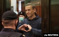 FILE - A still image taken from video footage shows Russian opposition leader Alexey Navalny making a hand heart gesture during the announcement of a court verdict in Moscow, Russia, Feb. 2, 2021. (Press Service of Simonovsky District Court)