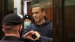 FILE - A still image taken from video footage shows Russian opposition leader Alexey Navalny making a hand heart gesture during the announcement of a court verdict in Moscow, Russia, Feb. 2, 2021.