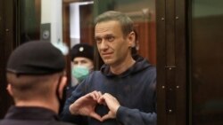 FILE - A still image taken from video footage shows Russian opposition leader Alexey Navalny making a hand heart gesture during the announcement of a court verdict in Moscow, Russia, Feb. 2, 2021.