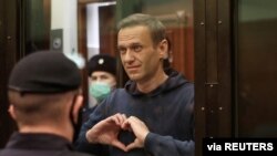 FILE - A still image taken from video footage shows Russian opposition leader Alexey Navalny making a hand heart gesture during the announcement of a court verdict in Moscow, Russia, Feb. 2, 2021.