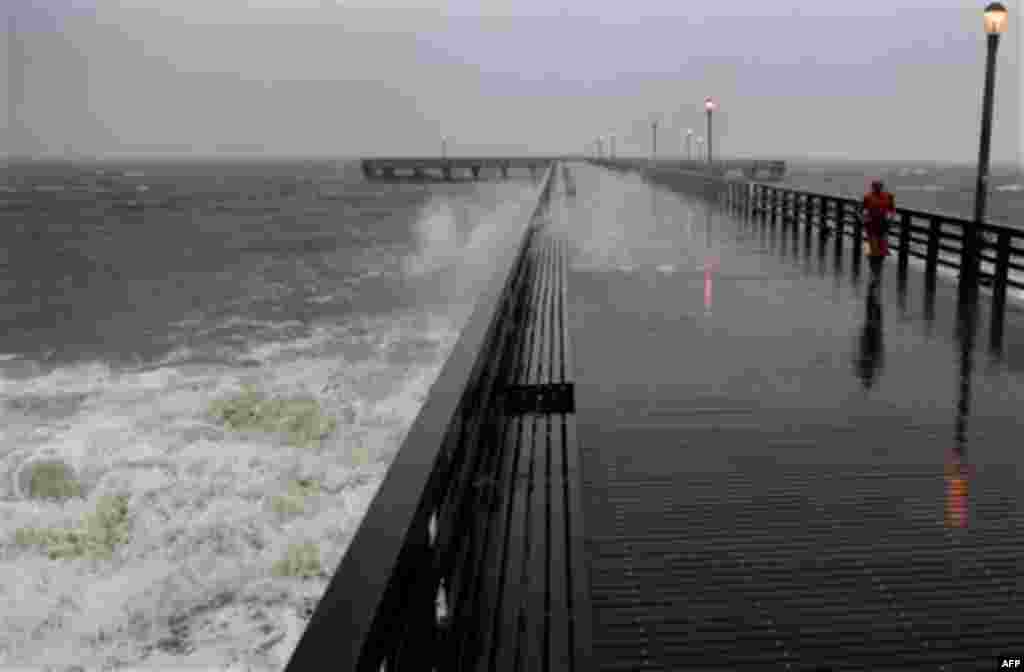 Gary Atlas, of Brighton Beach, N.Y., runs along the windswept Coney Island boardwalk in New York despite the onset of Hurricane Irene in the area Sunday, Aug. 28, 2011. Rainfall overflowed sewers and seawater lapped at sidewalks at the edges of New York C