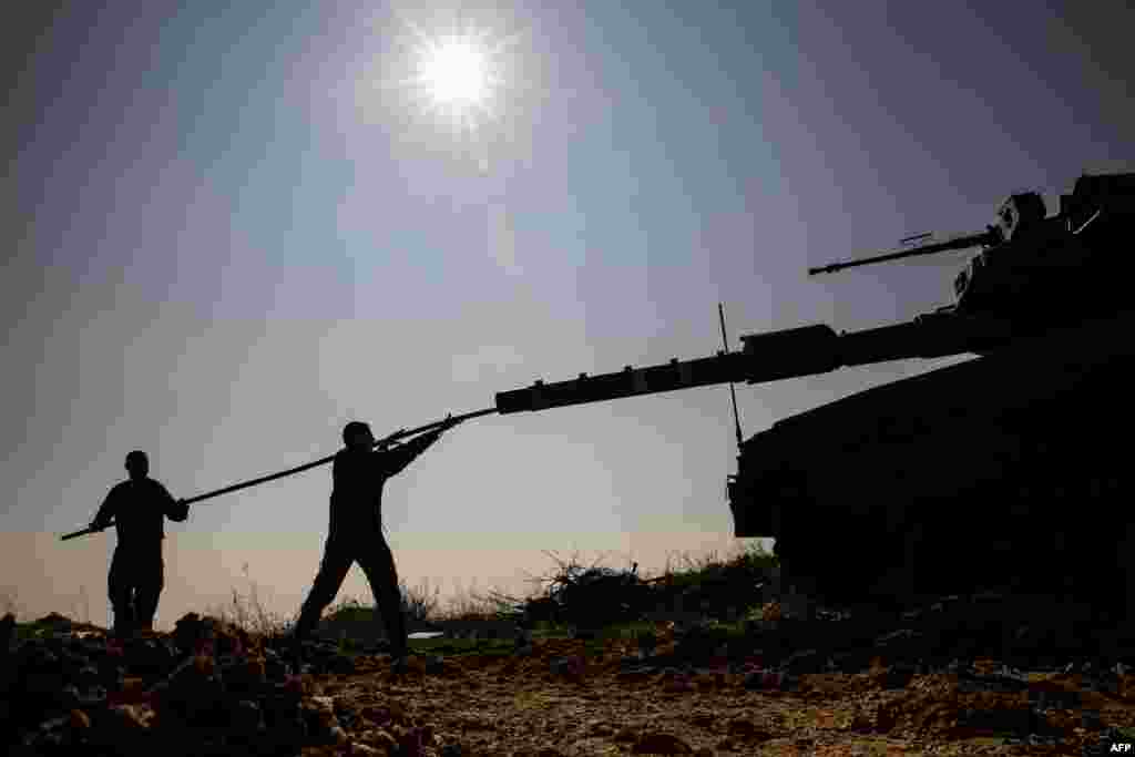 Israeli soldiers work on their Merkava tank as they hold a position along the Israeli border with Lebanon two days after an Israeli air strike killed six Hezbollah members in the Syrian-controlled side of the Golan Heights.