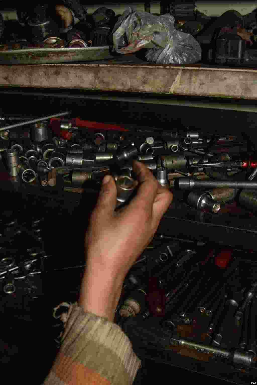 Hamad reaches for tools. Unlike his younger brother, Hamad also helps fix the car engines, John Owens/VOA.