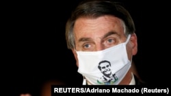 Brazil, Brasilia, Brazil's President Jair Bolsonaro speaks with journalists while wearing a protective face mask 