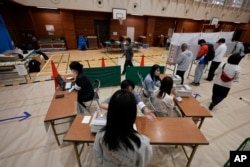 Petugas pemilu membantu pemilih di tempat pemungutan suara untuk pemilihan majelis rendah Jepang di Tokyo, 27 Oktober 2024. (Foto: AP)