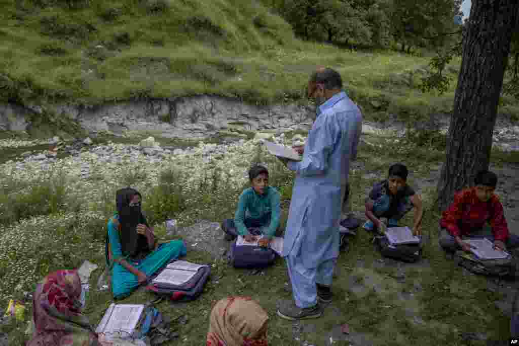 Kashmiri students listen to their teacher Ghulam Hassan during open air community classes in Tangmarg area northwest of Srinagar, Indian-controlled Kashmir.