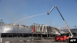 Sejumlah petugas SAR menyemprotkan air ke sebuah supermarket yang rusak akibat diserang drone Rusia di Odesa, Ukraina, 14 Agustus 2023. (Foto: Oleksandr Gimanov/ AFP)