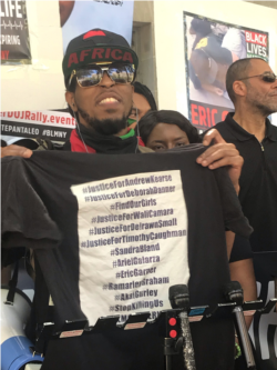 Director of Community Relations Ares Davoice holds up a shirt with names of black people killed by police, including Andrew Pierce. “I can’t breathe” was also among his last words. (L. Bonilla/VOA)