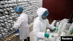 FILE - Medical personnel in protective gear prepare medicine for coronavirus-infected patients, at a pharmacy at Wuhan Tongji Hospital, in Wuhan, China, March 2, 2020. Chinese health officials say a first vaccine should soon be available.