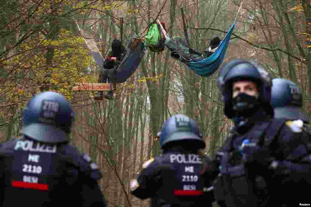 Police officers look on as demonstrators lie in hammocks hanging from trees during a protest against the extension of the A49 motorway, in a forest near Stadtallendorf, Germany.