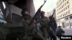 FILE - A Romanian soldier loads his automatic rifle as another one shoots during heavy fighting against pro-Ceausescu troops in central Bucharest, Romania, Dec. 23, 1989. 