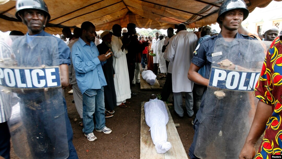 FILE - Security forces stand guard near the bodies of protesters, killed during a rally, in Conakry, Guinea, Oct.2, 2009.