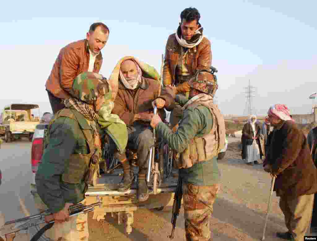 Kurdish security forces help an elderly man from the minority Yazidi sect on the outskirts of Kirkuk, Iraq, Jan. 17, 2015.