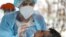 A healthcare worker takes a nasal swab sample from a merchant at a new coronavirus testing site geared at street vendors, at a sports center in the Puente Alto neighborhood of Santiago, Chile, July 10, 2020. 
