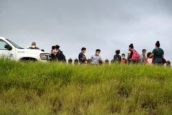 FILE - Asylum-seeking migrants from Central America are processed by the U.S. Border Patrol agents after crossing the Rio Grande into the United States from Mexico, in Penitas, Texas, July 8, 2021.
