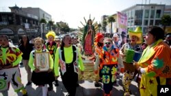 FILE - Clowns carry a statue of the Virgin of Guadalupe, as they arrive at the Basilica of Our Lady of Guadalupe in Mexico City, Dec. 14, 2015. 