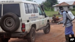 Ebola health workers spray disinfectant on an ambulance that was used to transport two people suspected of having the Ebola virus on the outskirts of Monrovia, Liberia, July 1, 2015.