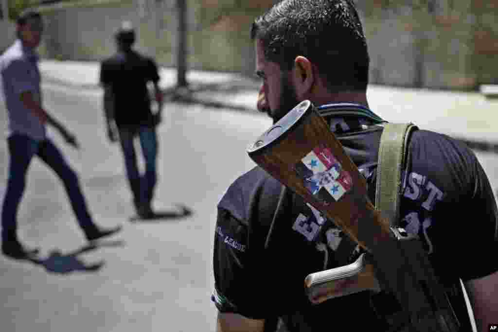 A Syrian military soldier holds his Ak-47 with a sticker of Syrian President Bashar Assad and Arabic that reads, "Syria is fine," as he stands guard at a check point on Baghdad street, in Damascus, August 21, 2013.