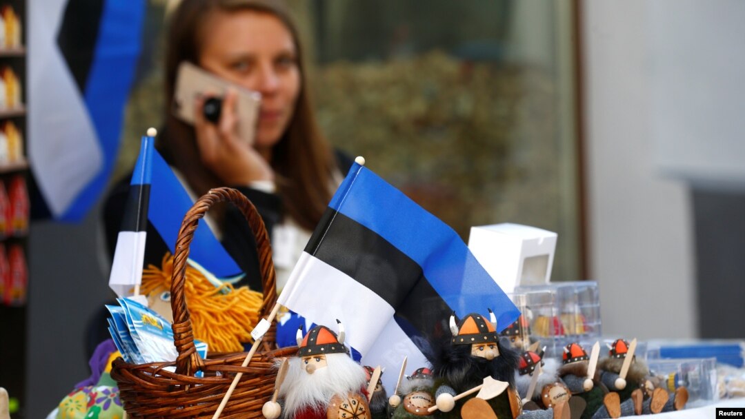 FILE - An Estonian national flag is seen as a street vendor speaks on her phone in Tallinn, Estonia, May 31, 2018.