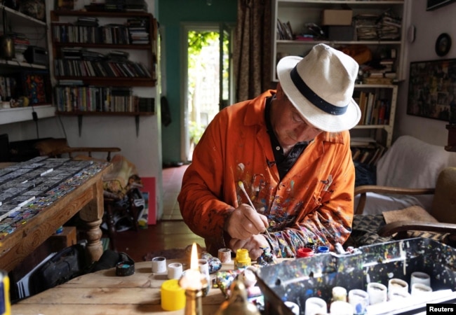 Ben Wilson, paints a tile piece in his home studio in Muswell Hill, London, Britain, August 21, 2023. (REUTERS/Anna Gordon)