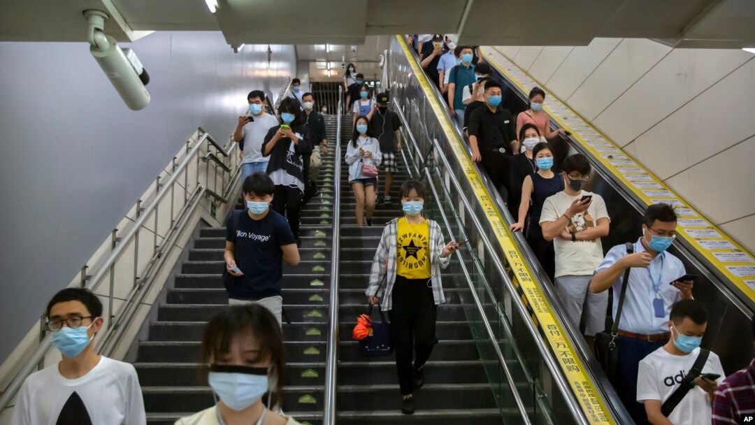 Commuters wearing face masks to protect against the spread of the new coronavirus walk through a subway station in Beijing, July 9, 2020. 