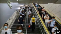 Commuters wearing face masks to protect against the spread of the new coronavirus walk through a subway station in Beijing, July 9, 2020. 