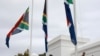 A policeman adjusts South African flags to half-mast outside parliament in Cape Town, South Africa, Nov. 25, 2020.