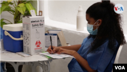Una trabajadora de salud anota los datos de los pacientes en un centro de vacunación en Caracas, Venezuela. Imagen tomada de video, domingo 11 de abril de 2021.