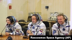 In this handout photo released by Roscosmos, actress Yulia Peresild, left, film director Klim Shipenko, right, and cosmonaut Anton Shkaplerov speak with their relatives through a safety glass prior the launch at the Baikonur Cosmodrome, Kazakhstan, Tuesday, Oct. 5, 2021. 