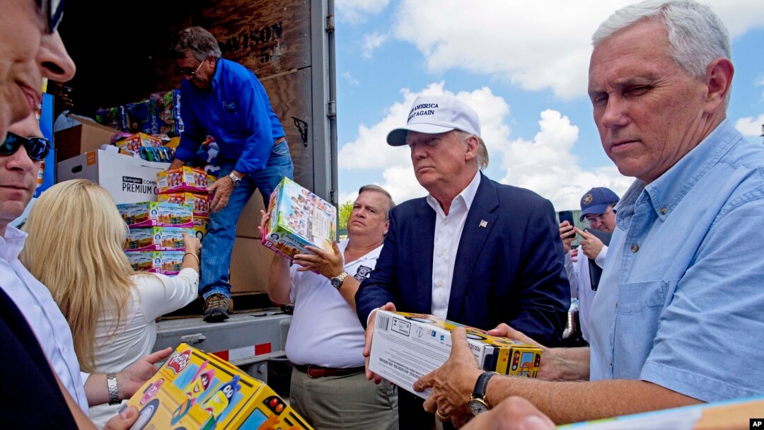 Calon presiden AS dari Partai Republik Donald Trump dan pasangan wapresnya, Gubernur India Mike Pence, membantu menurunkan psokan bantuan untuk korban banjir di Louisiana (19/8). (AP/Max Becherer)