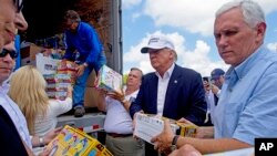 Calon presiden AS dari Partai Republik Donald Trump dan pasangan wapresnya, Gubernur India Mike Pence, membantu menurunkan psokan bantuan untuk korban banjir di Louisiana (19/8). (AP/Max Becherer)