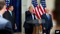 FILE - Presiden Trump Donald Trump, didampingi oleh Wakil Presiden Mike Pence (kanan) dan Sekretaris Negara bagian Kansas Kris Kobach pada 19 Juli, 2017