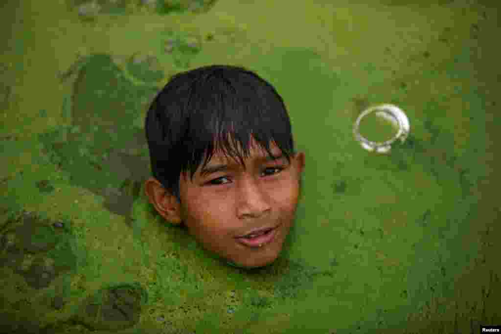 A boy swims in a pond covered with algae in Bhaktapur, Nepal.