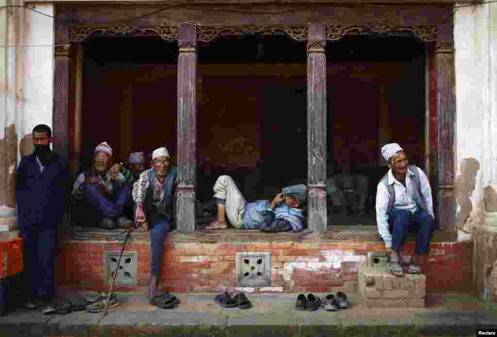 Beberapa pria menghabiskan waktu mereka duduk di pinggir sebuah jalan di kota Bhaktapur, Nepal.