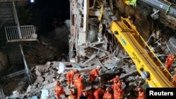 Rescue workers work next to a crane at the site where a hotel building collapsed in Suzhou, Jiangsu province, China, July 12, 2021. (cnsphoto via Reuters)