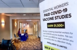 FILE - A poster advertises a hunt for volunteers for a study of a possible COVID-19 vaccine, in Binghamton, N.Y., July 27, 2020.