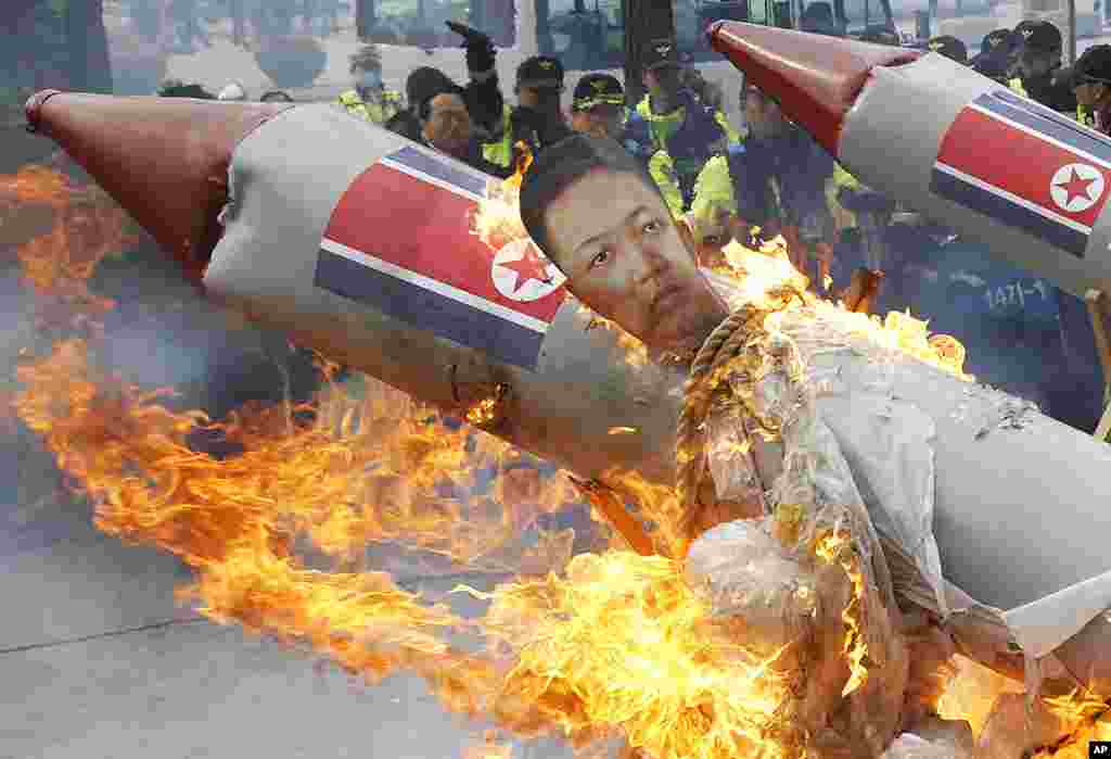 Policemen watch as protesters, from conservative, right-wing and anti-North Korean civic groups, burn an effigy of North Korean leader Kim Jong-Un bound on a mock North Korean missile during a protest in Seoul, April 13, 2012. (Reuters)