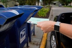 FILE - A person drops applications for mail-in-ballots into a mailbox in Omaha, Neb., Aug. 18, 2020.