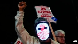 A Boeing worker wears a mask with a digital "strike" sign as employees picket after union members voted overwhelmingly to reject a contract offer and go on strike Sept. 13, 2024, outside the company's factory in Renton, Washington. 