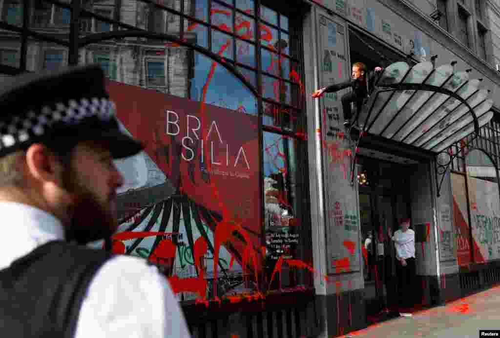 An activist splashes red paint over the facade of the Brazilian embassy in London during an Extinction Rebellion climate change protest.