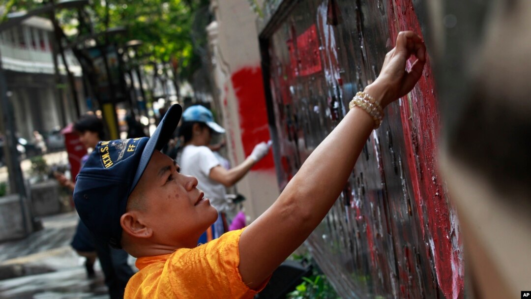 Para demonstran anti-pemerintah membersihkan grafiti dari gerbang utama markas besar Kepolisian Kerajaan Thailand di Bangkok, Thailand (1/3).