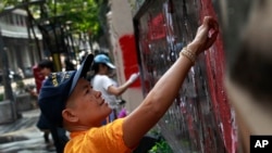 Para demonstran anti-pemerintah membersihkan grafiti dari gerbang utama markas besar Kepolisian Kerajaan Thailand di Bangkok, Thailand (1/3).