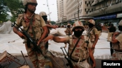 Tentara paramiliter berjaga-jaga dekat tenda-tenda puluhan pendukung partai MQM setelah demonstrasi di Karachi, Pakistan (22/8). (Reuters/Akhtar Soomro)