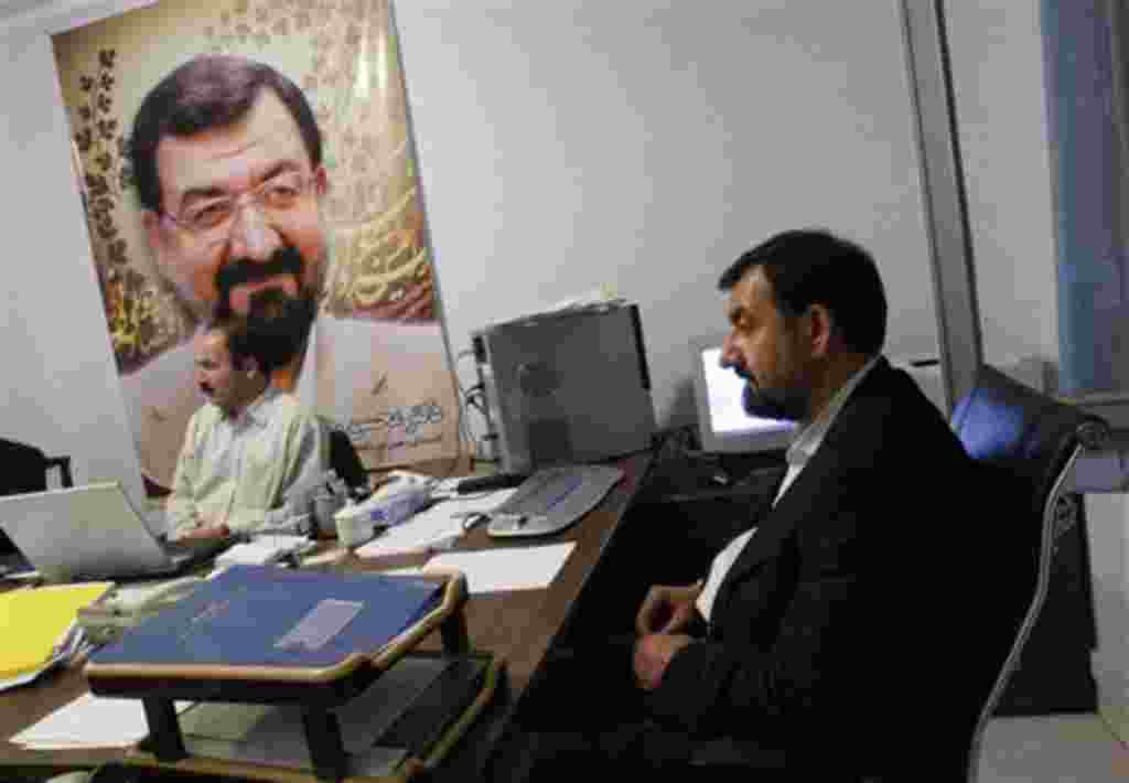 Iranian presidential hopeful Mohsen Rezaei, right, is seen in his election campaign headquarters as an enlarged photo of him is seen on the wall in Tehran on Tuesday, May 26, 2009. The only conservative challenger to President Mahmoud Ahmadinejad in Iran