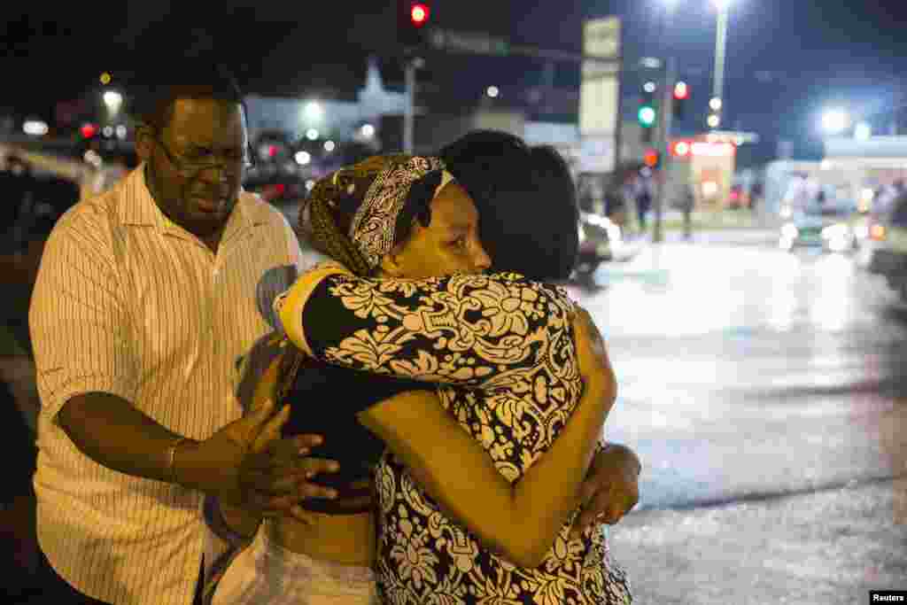 Demonstrators weep on each others shoulders as masked individuals break into a store in Ferguson, Aug. 16, 2014.