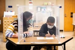 FILE - Pre-kindergarten teacher Sarah McCarthy works with a student at Dawes Elementary in Chicago, Jan. 11, 2021.